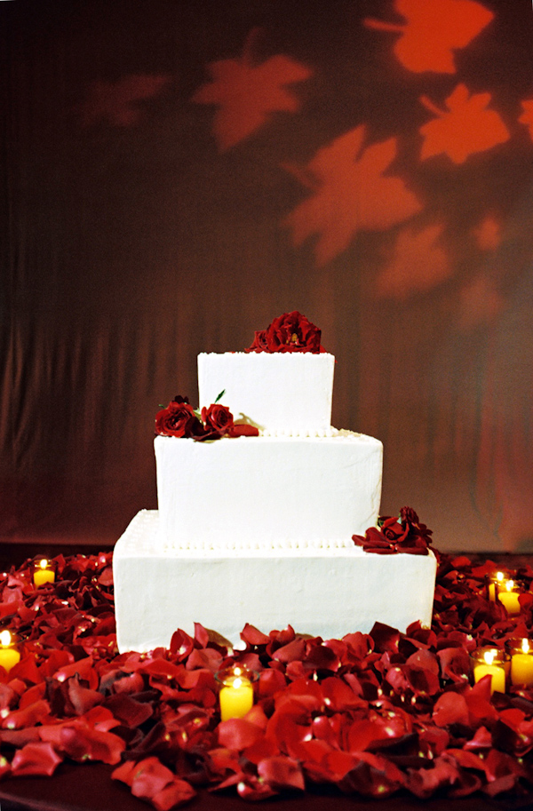 white wedding cake with red floral decoration photo by Yvette Roman Photography
